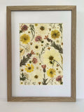 Buttercup pressed flower artwork in a light oak frame