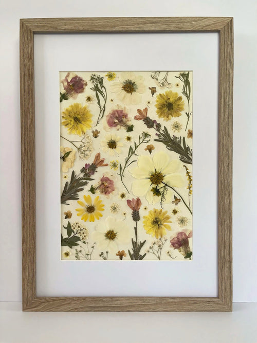 Buttercup pressed flower artwork in a light oak frame