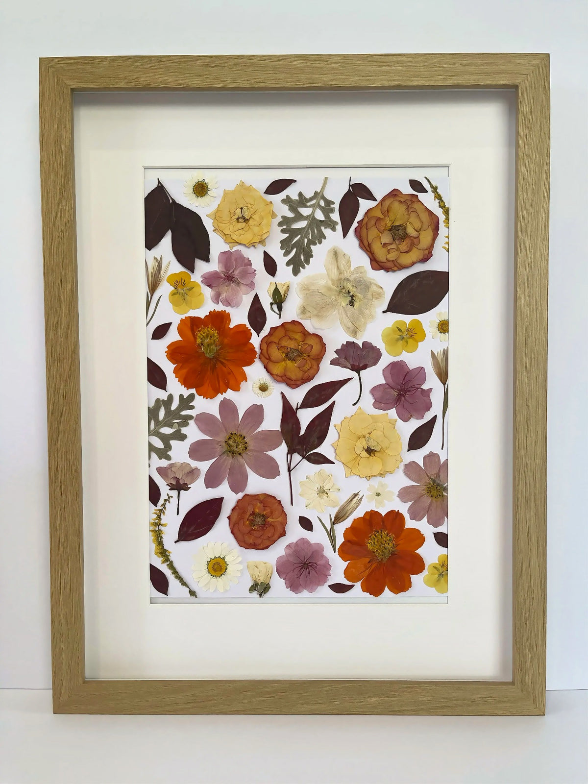 Nectar pressed flower artwork in a light oak frame